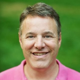 A man with short hair and a pink shirt.