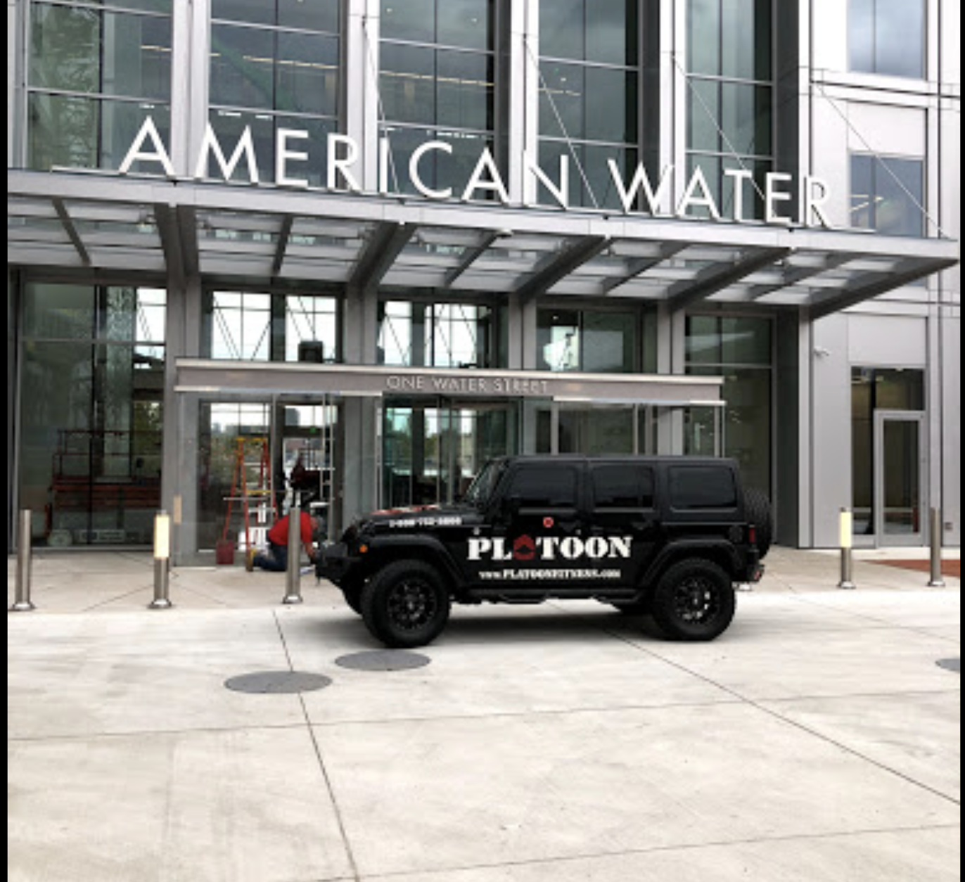 A black jeep parked in front of the american water company building.