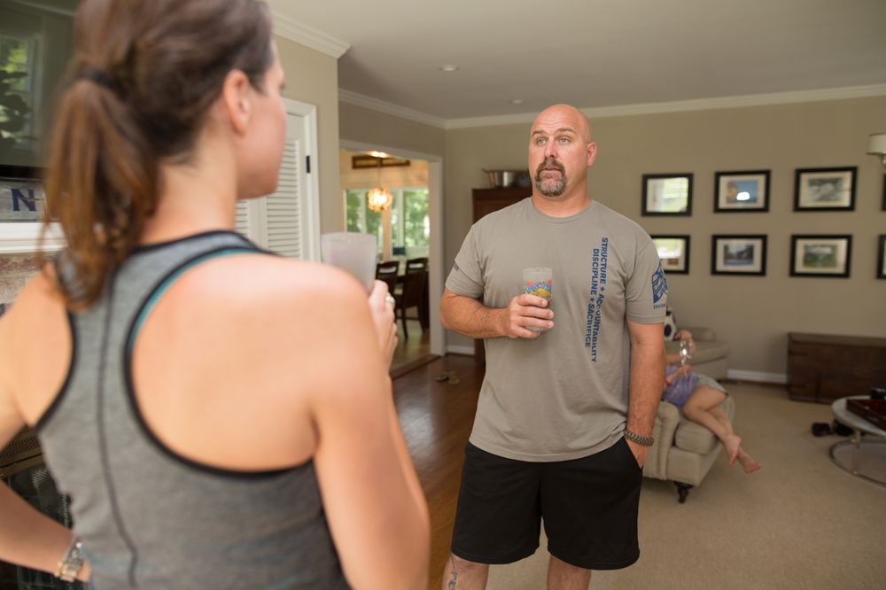 A man and woman standing in front of another man holding a drink.