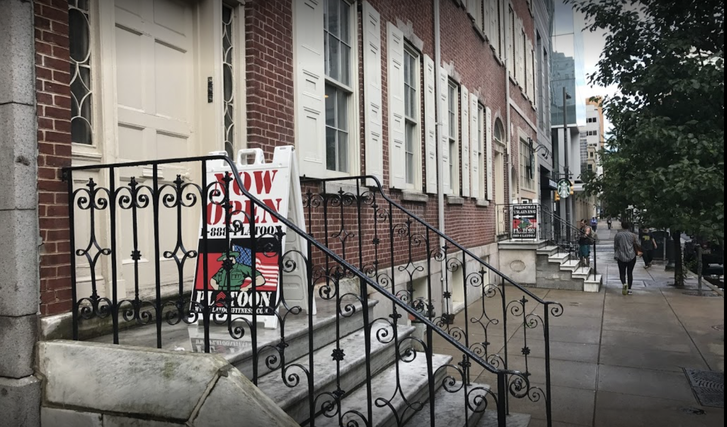 A sidewalk with steps and iron railings on it.