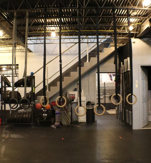 A gym with several large hanging tires and stairs.