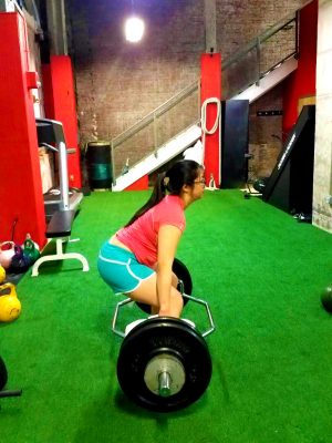 A woman squatting on the ground with a barbell.